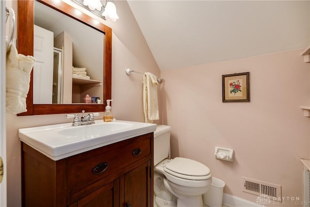 bathroom with toilet, lofted ceiling, and vanity