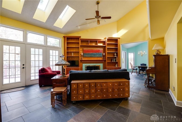 living room with ceiling fan with notable chandelier, french doors, and high vaulted ceiling