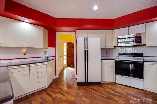 kitchen with white cabinetry, dark hardwood / wood-style flooring, and white appliances