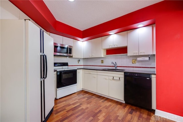 kitchen with white fridge, white cabinetry, black dishwasher, electric range, and sink