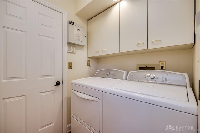 laundry room featuring separate washer and dryer and cabinets