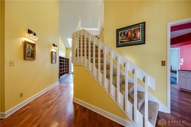 staircase featuring high vaulted ceiling and wood-type flooring