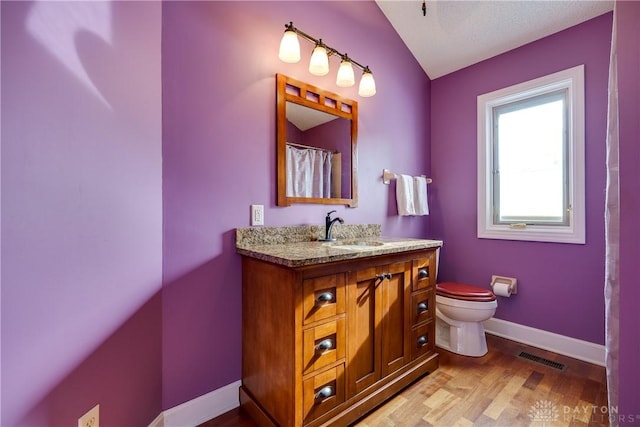 bathroom with hardwood / wood-style floors, toilet, vanity, and vaulted ceiling