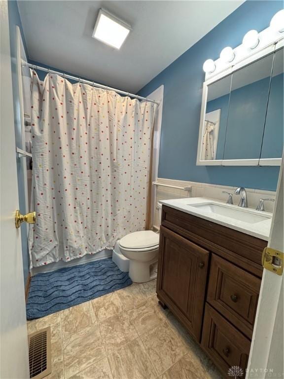 bathroom featuring vanity, curtained shower, and toilet