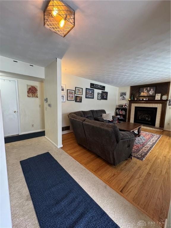 living room with a brick fireplace and light hardwood / wood-style flooring