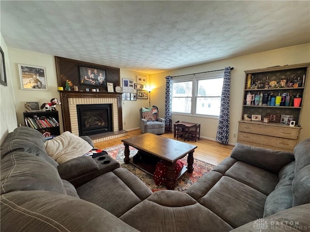 living room featuring light hardwood / wood-style flooring, a fireplace, and a textured ceiling