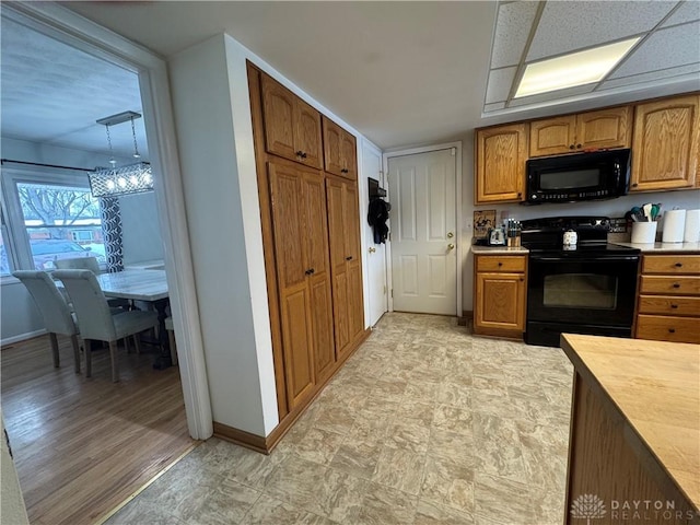 kitchen with pendant lighting, black appliances, and an inviting chandelier