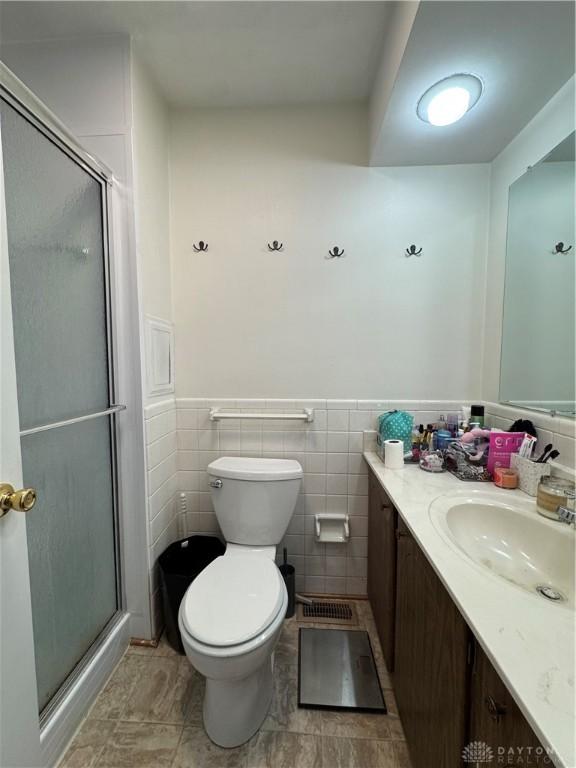 bathroom featuring vanity, tile walls, toilet, and walk in shower