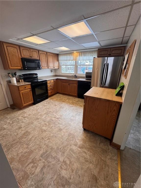 kitchen with sink, a paneled ceiling, and black appliances