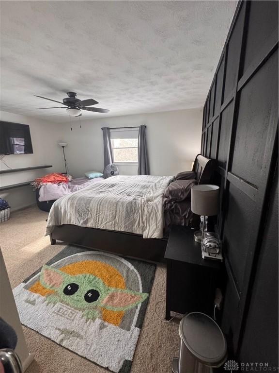 carpeted bedroom featuring ceiling fan and a textured ceiling