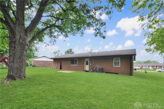 rear view of property featuring cooling unit and a lawn