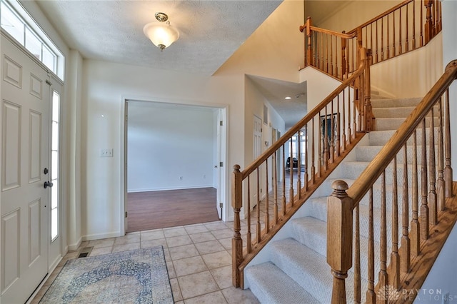 entrance foyer with visible vents, light tile patterned flooring, a textured ceiling, and baseboards