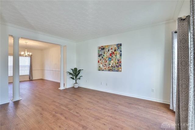 unfurnished room with decorative columns, ornamental molding, a chandelier, and wood finished floors