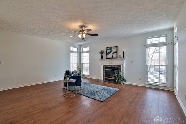 unfurnished room featuring dark wood-style flooring, a textured ceiling, baseboards, and a premium fireplace