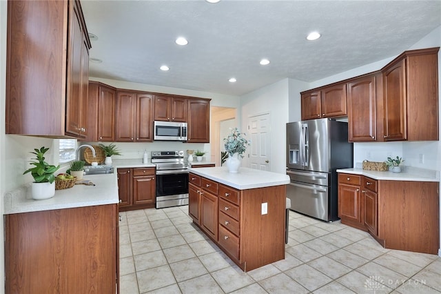 kitchen featuring recessed lighting, light countertops, appliances with stainless steel finishes, a kitchen island, and a sink