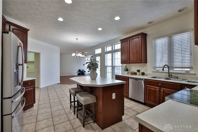 kitchen with stainless steel appliances, light countertops, decorative light fixtures, and a center island