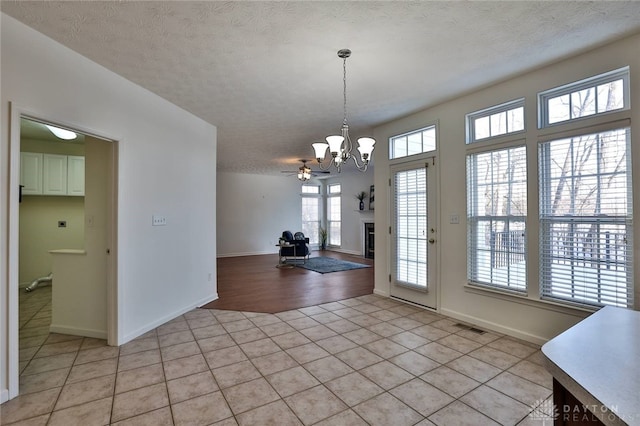 unfurnished dining area featuring visible vents, a fireplace, a textured ceiling, and light tile patterned floors