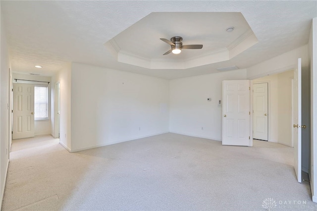 empty room featuring light carpet, ornamental molding, and a raised ceiling