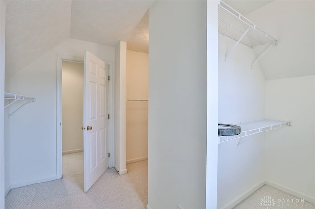 spacious closet featuring vaulted ceiling and light colored carpet