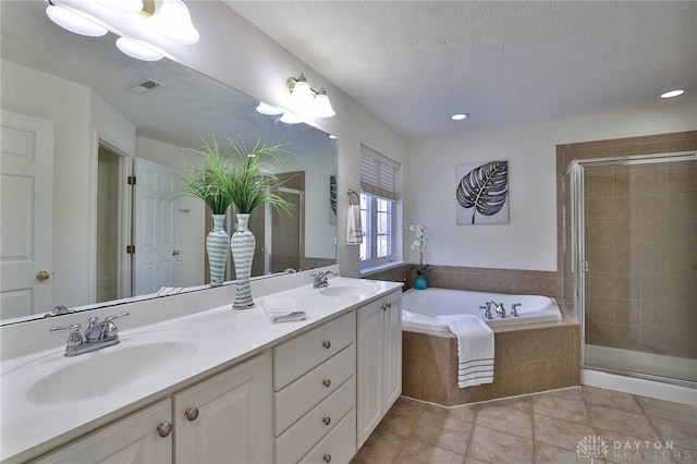 bathroom featuring a textured ceiling, a stall shower, a sink, and tile patterned floors