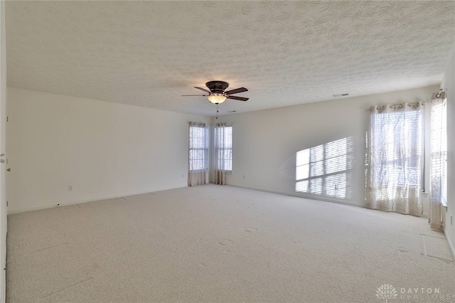 spare room with light carpet, a textured ceiling, and a ceiling fan