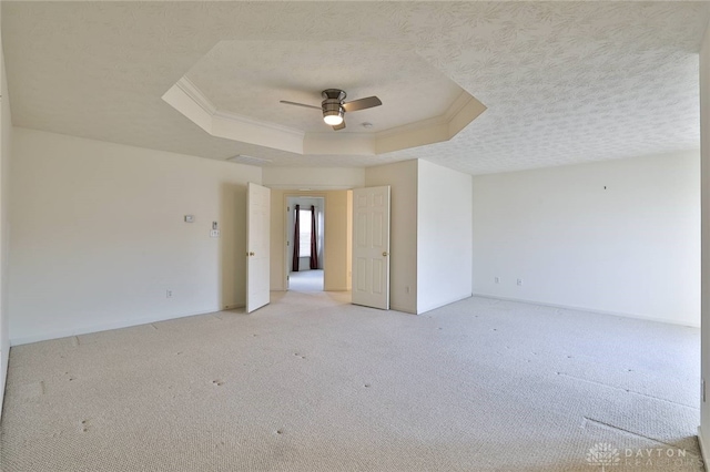 unfurnished room with a textured ceiling, ornamental molding, light carpet, and a raised ceiling