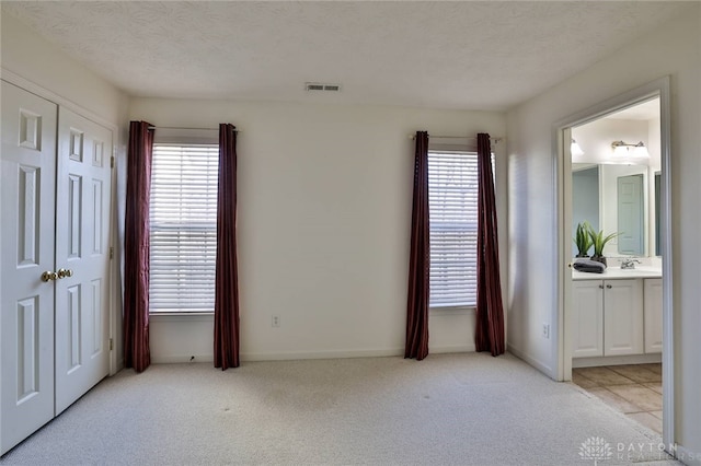 bedroom with light carpet, visible vents, and a textured ceiling