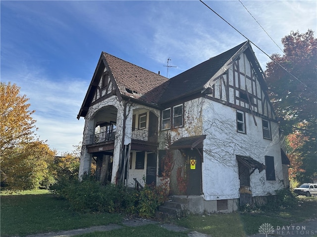 view of side of property with a balcony and a lawn