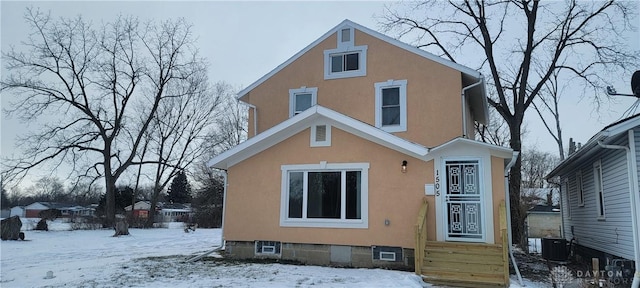 snow covered rear of property featuring central AC