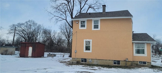 snow covered property featuring a storage shed