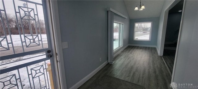 doorway to outside with dark hardwood / wood-style floors, a chandelier, and vaulted ceiling