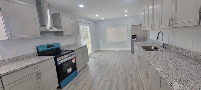 kitchen featuring sink, light hardwood / wood-style flooring, appliances with stainless steel finishes, a textured ceiling, and wall chimney exhaust hood