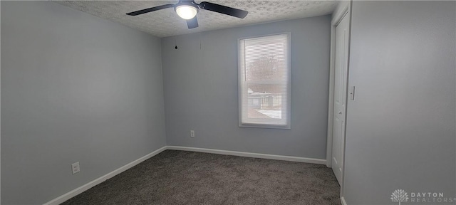 empty room featuring ceiling fan, a textured ceiling, and dark colored carpet