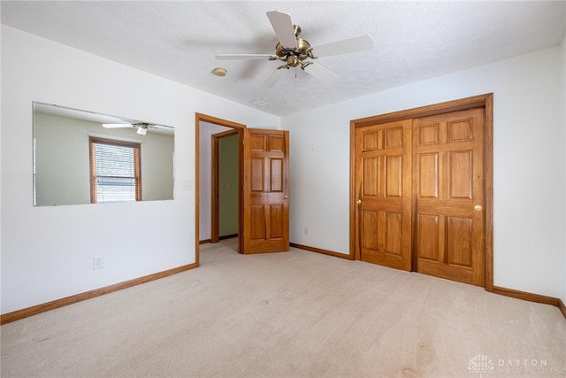 unfurnished bedroom with a textured ceiling, light colored carpet, and ceiling fan