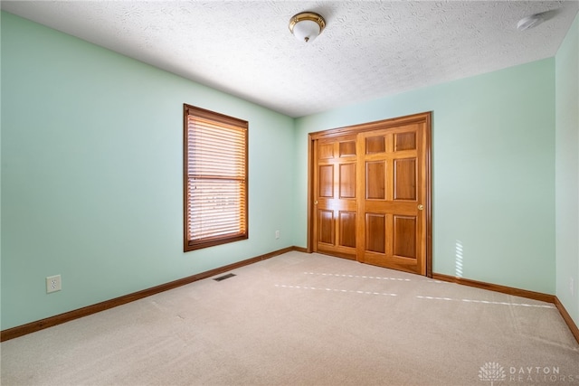 unfurnished bedroom with light carpet and a textured ceiling