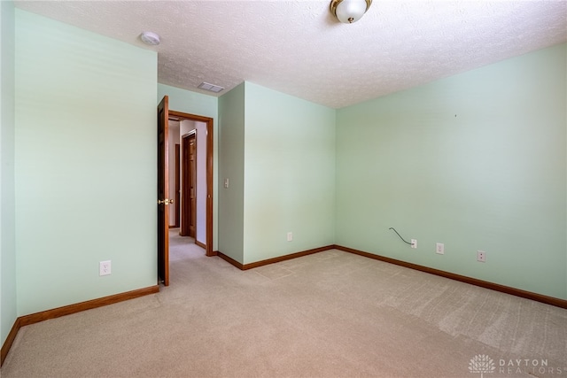 unfurnished room featuring light colored carpet and a textured ceiling