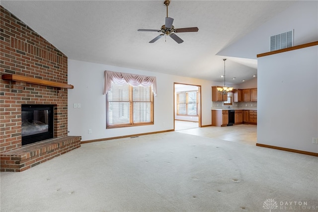 unfurnished living room featuring ceiling fan with notable chandelier, a textured ceiling, lofted ceiling, light carpet, and a brick fireplace