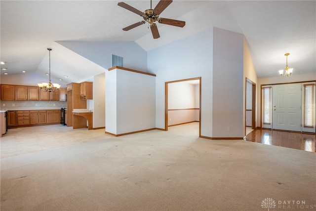 unfurnished living room featuring ceiling fan with notable chandelier, light colored carpet, and high vaulted ceiling