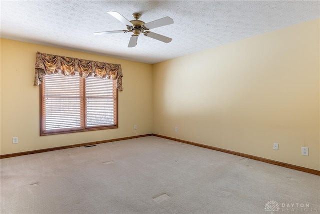 empty room featuring a textured ceiling, light colored carpet, and ceiling fan