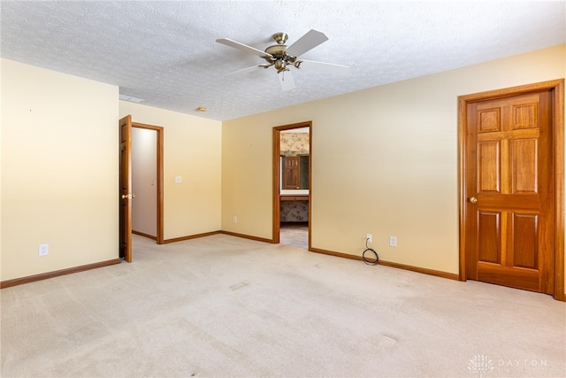 empty room featuring ceiling fan, light colored carpet, and a textured ceiling