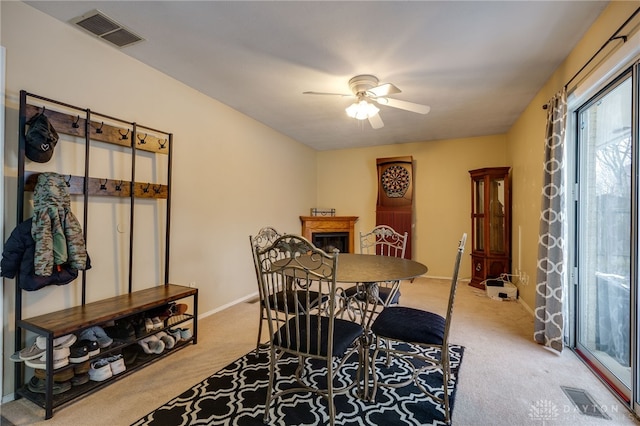 dining space with light carpet and ceiling fan