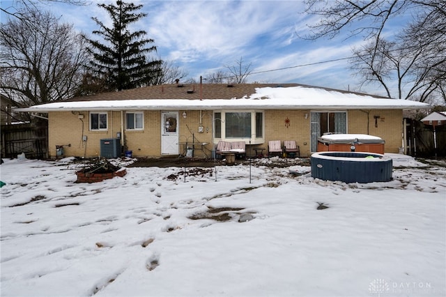 snow covered rear of property featuring a hot tub and central AC