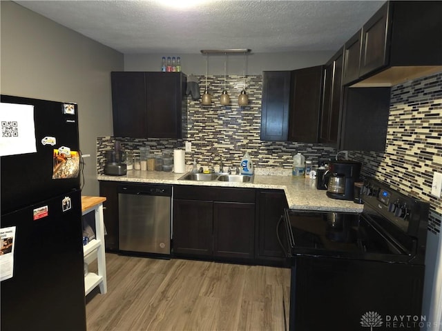 kitchen featuring sink, backsplash, black appliances, a textured ceiling, and light wood-type flooring