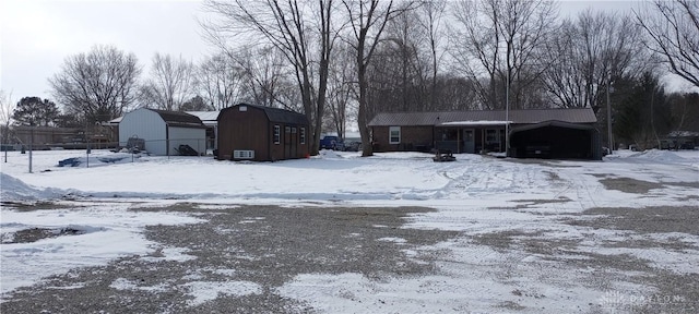 yard layered in snow with a detached garage and an outbuilding