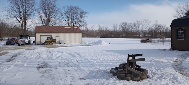 yard layered in snow with an outbuilding and a detached garage