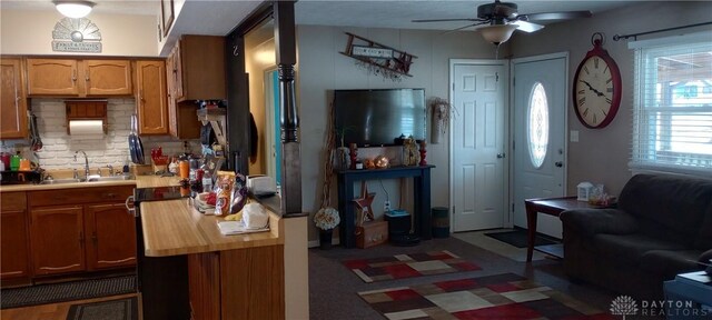 kitchen featuring ceiling fan, light countertops, decorative backsplash, brown cabinets, and a sink