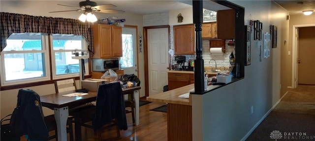 kitchen featuring brown cabinets, a ceiling fan, a peninsula, decorative backsplash, and baseboards