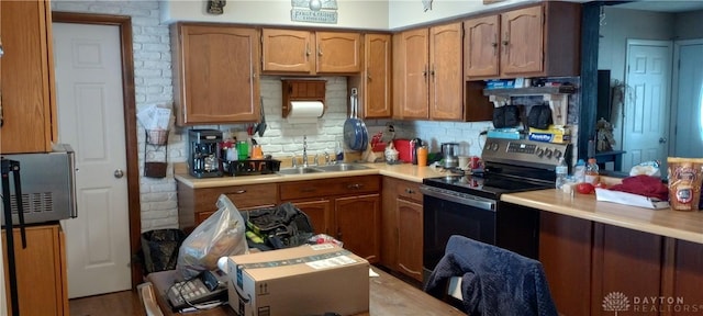 kitchen with range hood, stainless steel electric range, light countertops, and a sink