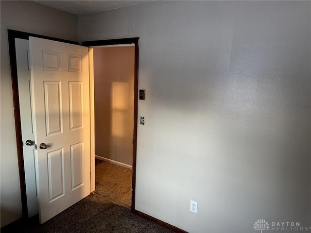 empty room with dark carpet and baseboards