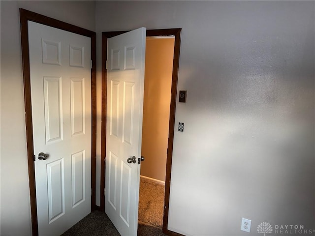 hall featuring dark colored carpet